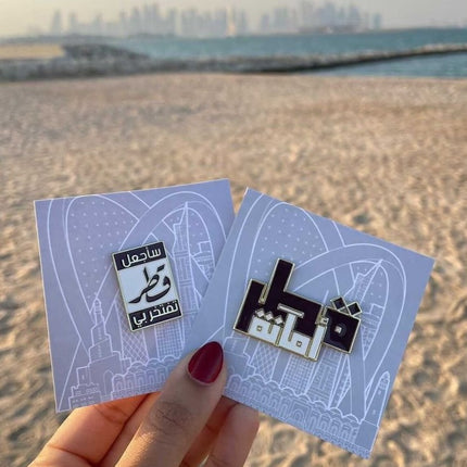 Qatar pin with arabic text holding