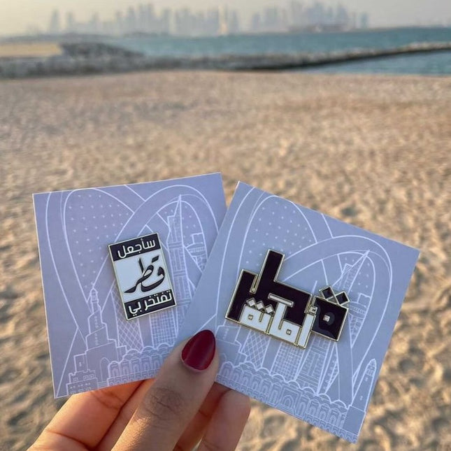 Qatar pin with arabic text holding